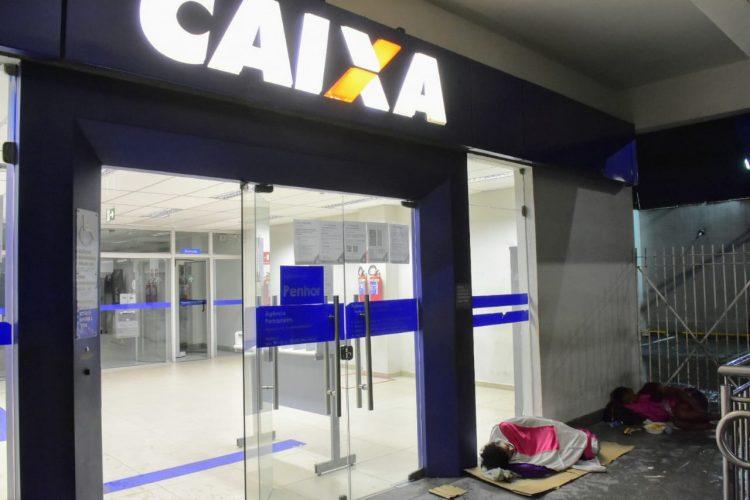 Pessoas dormem no chão à espera de atendimento na Caixa em Natal;