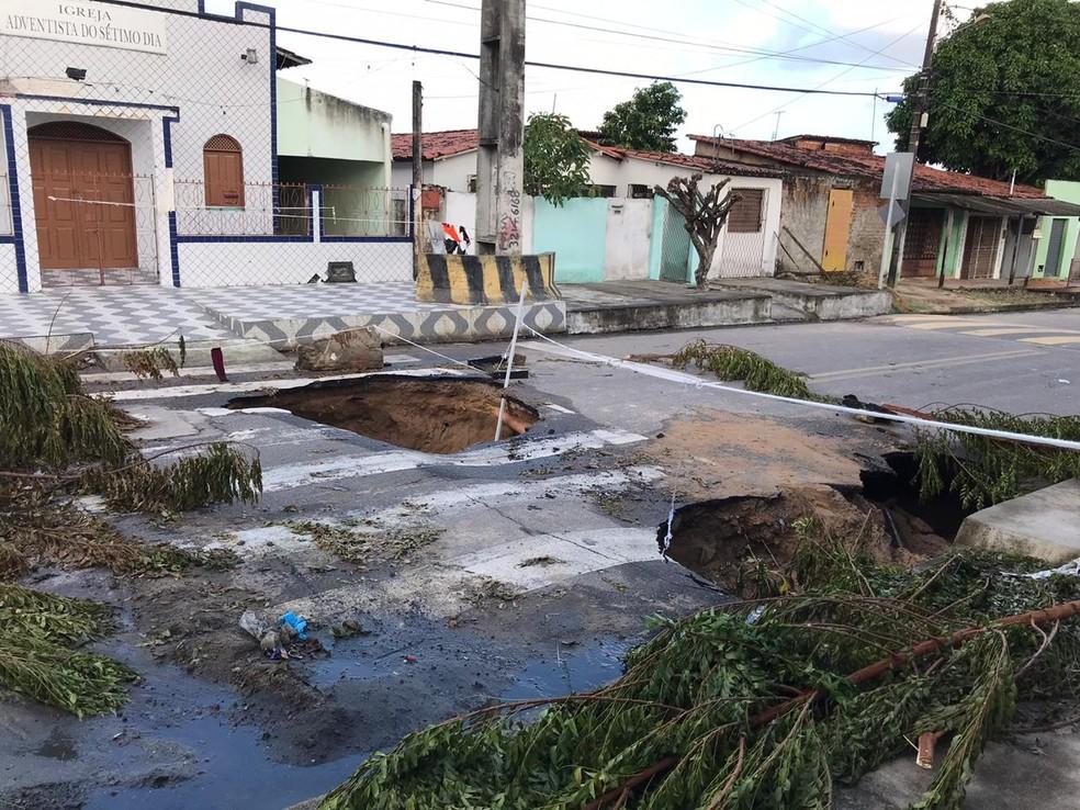 Asfalto cede, abre buracos e moradores interditam rua com galhos e cordas na Zona Norte de Natal