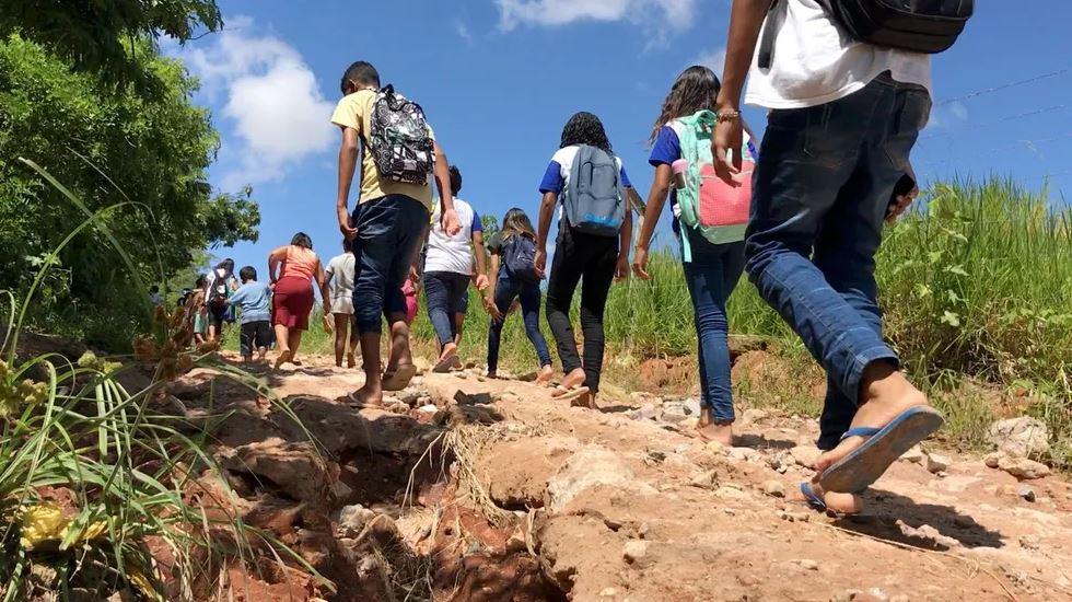 Sem transporte público, crianças caminham 3 quilômetros e atravessam córrego para chegar à escola em Natal