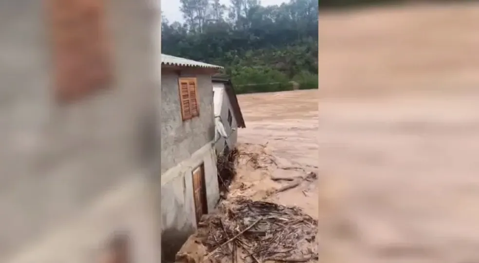 mostra parte de casa sendo levada pela água após cheia de rio em SC